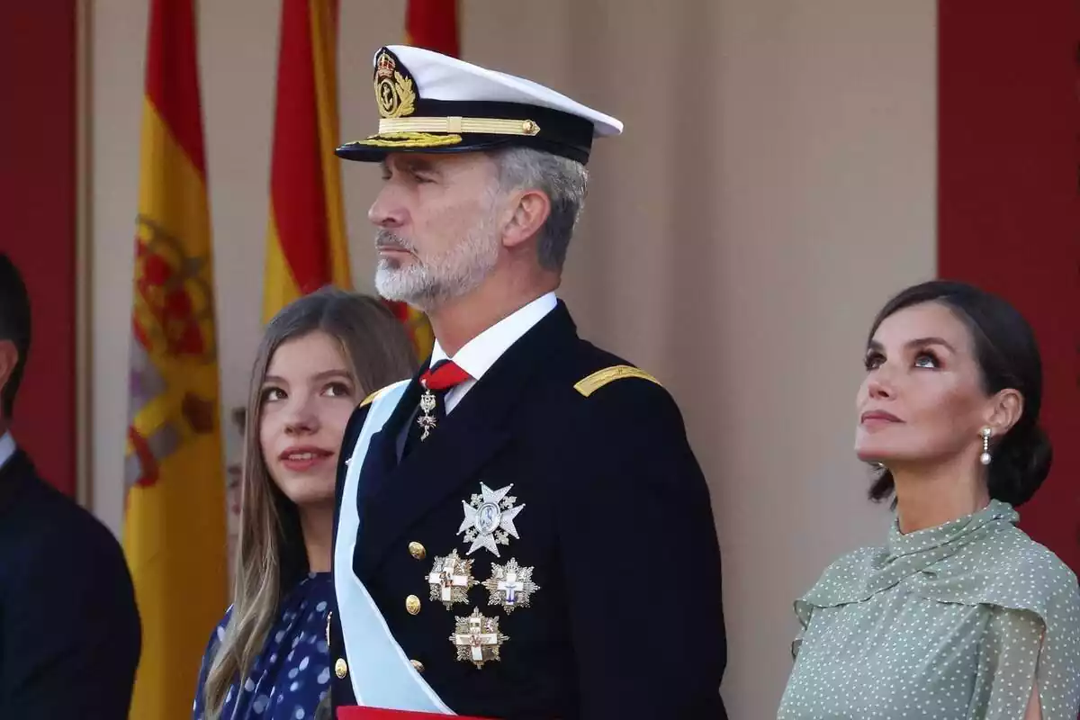 Pla mitjà del rei Felip VI amb cara seriosa a la desfilada militar del 12 d'octubre amb la reina Letizia al seu costat esquerre mirant al cel i la infanta Sofia a la seva dreta mirant el seu pare