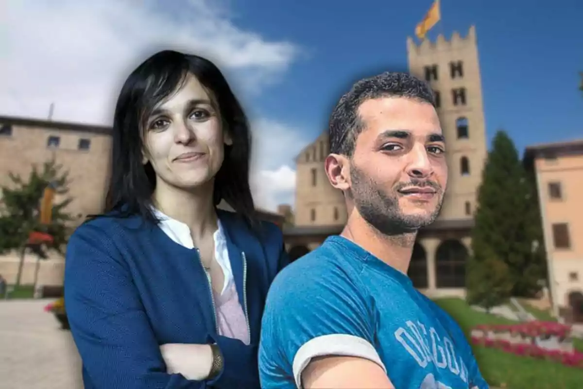 Dos personas posan frente a un edificio histórico con una torre y una bandera ondeando en la parte superior.