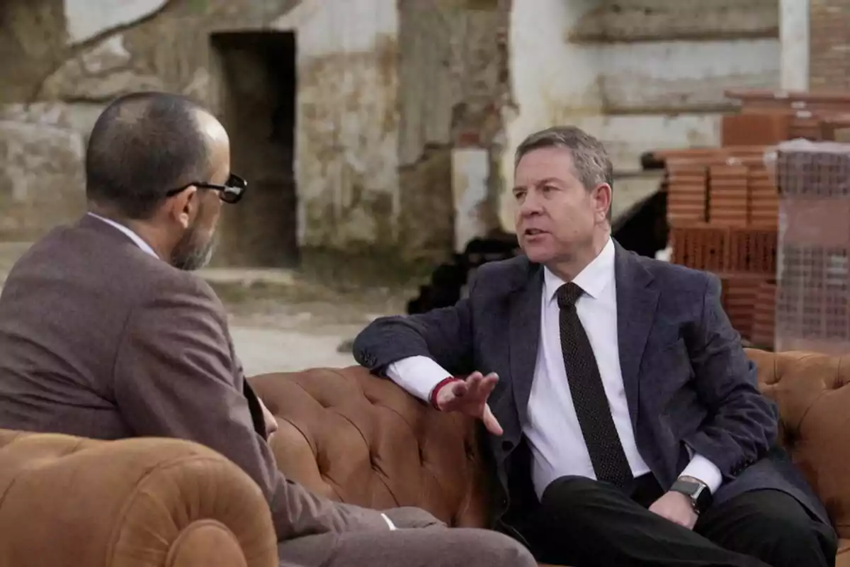 Risto Mejide i Emiliano García-Page asseguts en un sofà de cuir conversen en un entorn industrial amb parets de maó i fons desgastat a Viajando con Chester. Risto Mejide i Emiliano García-Page asseguts en un sofà de cuir conversen en un entorn industrial amb parets de maó i fons desgastat a Viajando con Chester.