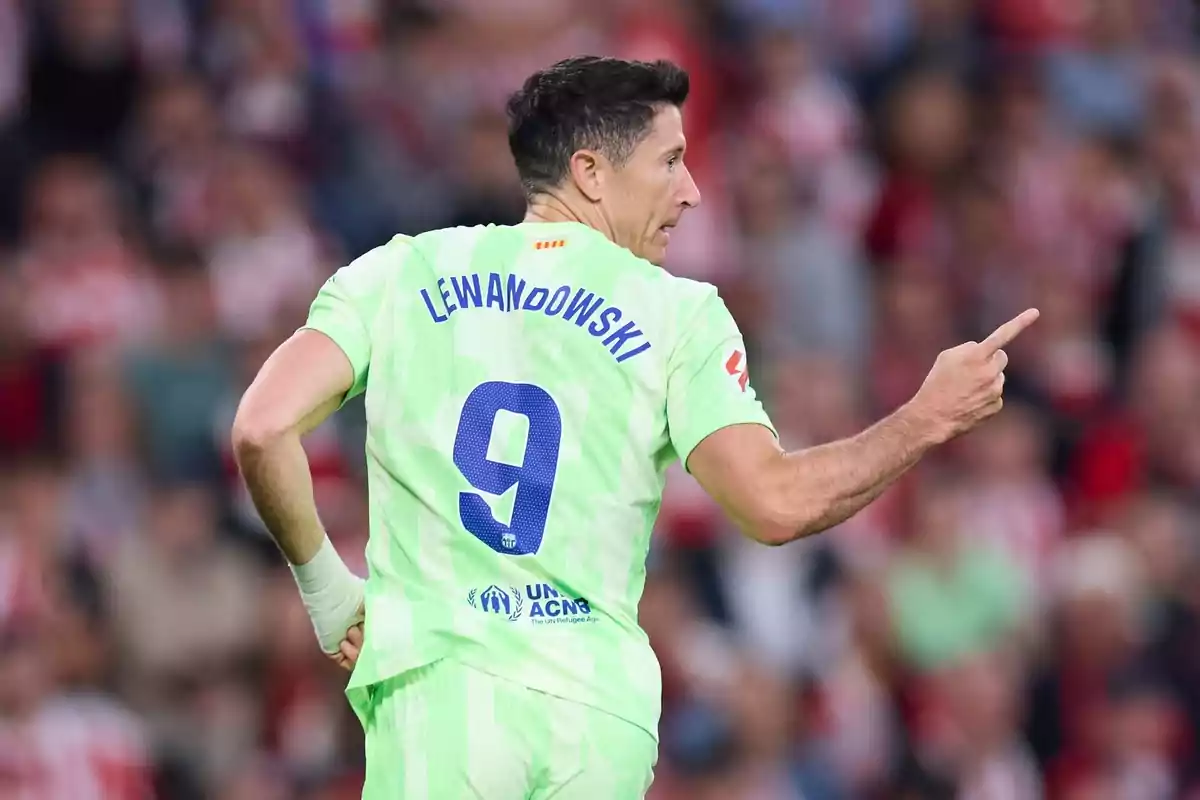 Soccer player in a light green uniform with the number 9 on his back pointing to the right in a stadium full of spectators Soccer player in a light green uniform with the number 9 on his back pointing to the right in a stadium full of spectators