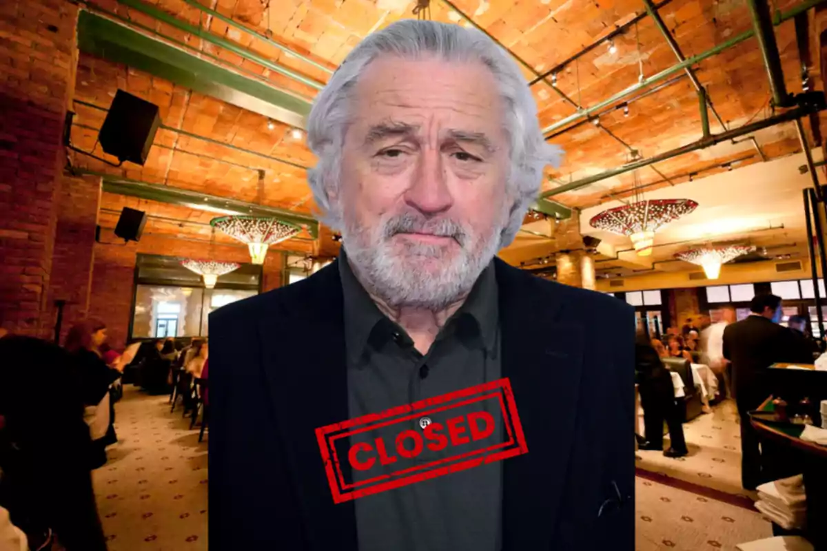 Robert De Niro, is standing in a fancy restaurant with a red sign that says "CLOSED" over his chest.