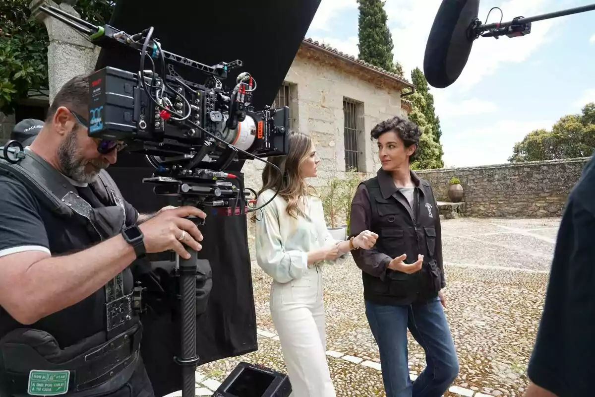 Un càmera grava Amaia Salamanca i Blanca Romero conversant en un plató de rodatge a l'aire lliure a Pura Sangre. Un càmera grava Amaia Salamanca i Blanca Romero conversant en un plató de rodatge a l'aire lliure a Pura Sangre.