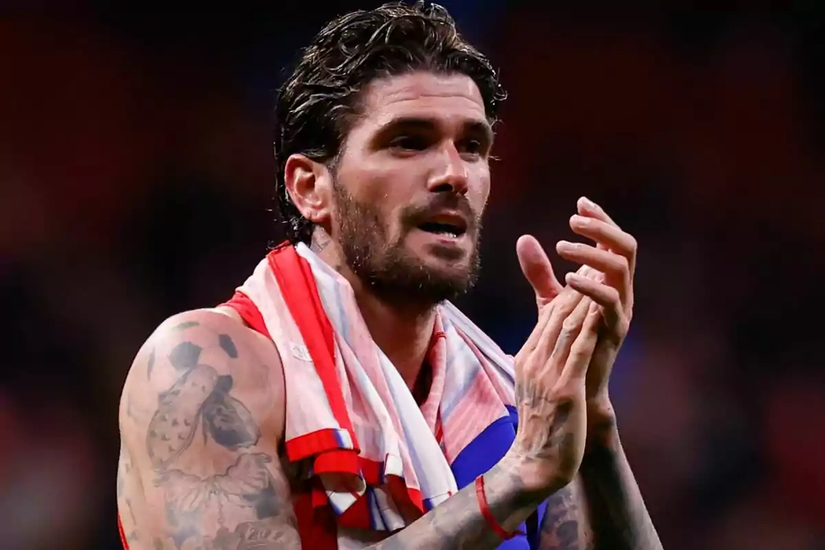A football player applauding with a t-jersey and a scarf on his shoulders.