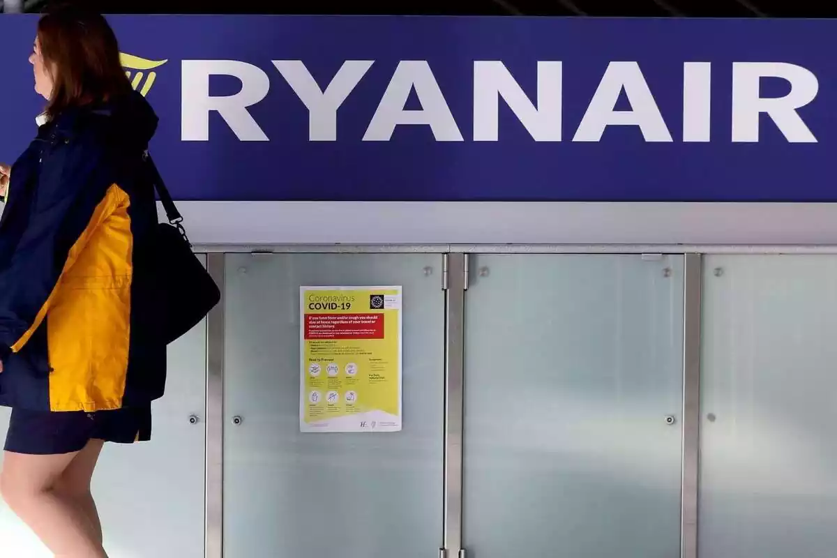 Una dona passa pel costat d'un cartell de Ryanair a la terminal un de l'aeroport de Dublín.