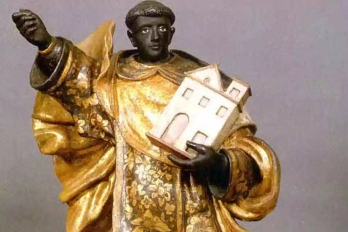 Una estàtua d'un sant amb túnica daurada sostenint un model d'edifici a la seva mà esquerra. Una estàtua d'un sant amb túnica daurada sostenint un model d'edifici a la seva mà esquerra.