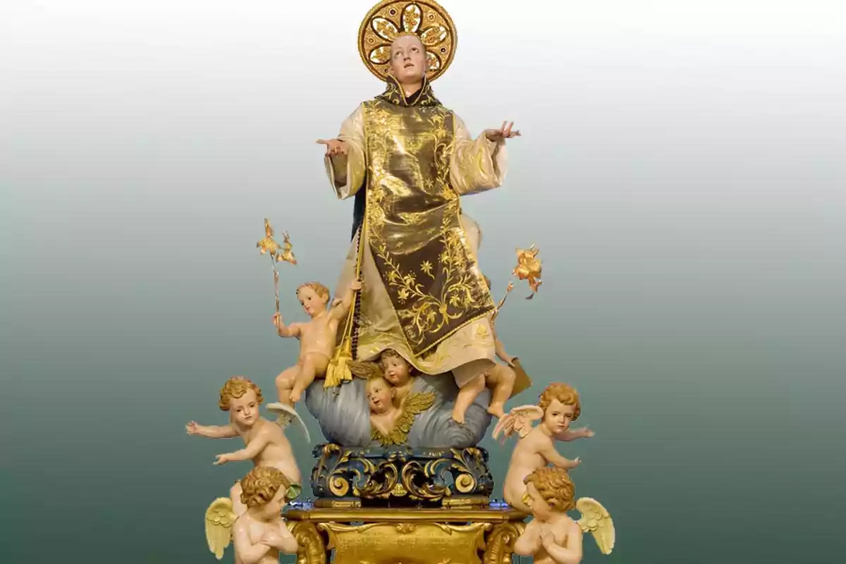 Escultura religiosa d’un sant amb túnica daurada envoltat de diversos àngels petits sobre una base decorada Escultura religiosa d’un sant amb túnica daurada envoltat de diversos àngels petits sobre una base decorada