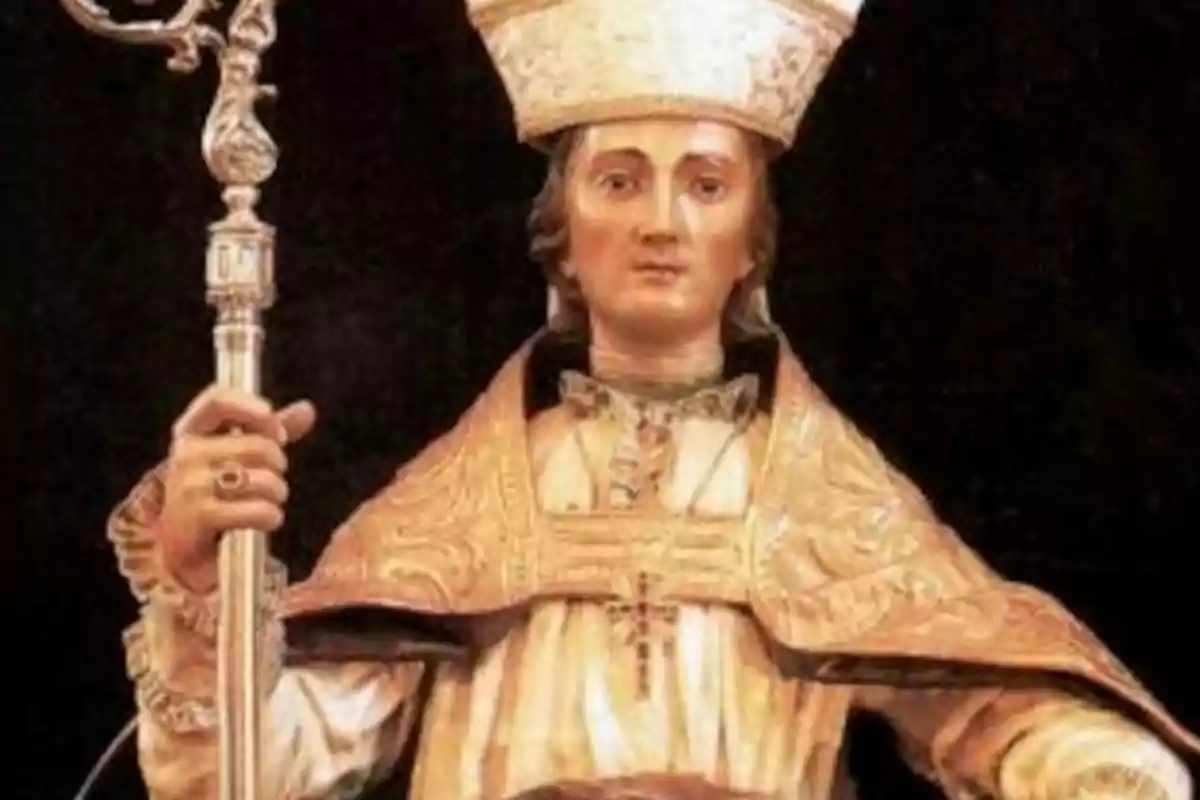 Figura religiosa vestida amb ornaments daurats i mitra sostenint un bàcul a la mà dreta sobre un fons fosc Figura religiosa vestida amb ornaments daurats i mitra sostenint un bàcul a la mà dreta sobre un fons fosc