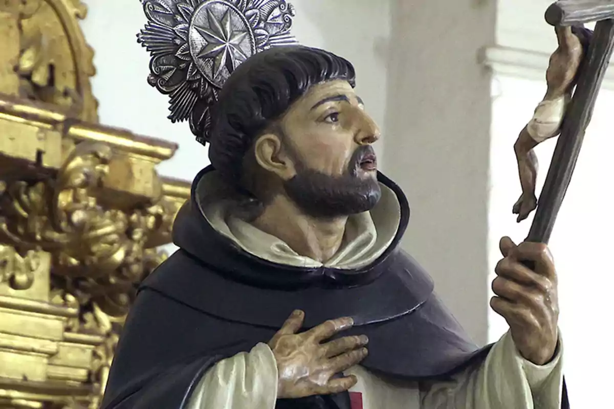 Una estàtua religiosa d'un sant amb un halo decoratiu sostenint un crucifix en un entorn d'església amb detalls daurats. Una estàtua religiosa d'un sant amb un halo decoratiu sostenint un crucifix en un entorn d'església amb detalls daurats.