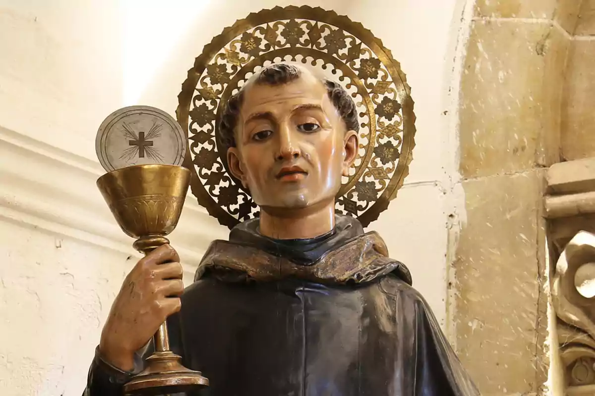 Escultura religiosa d’un sant amb aureola daurada sostenint un calze i una hòstia