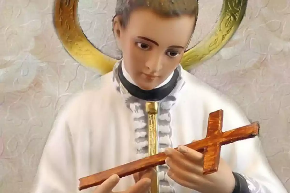 Escultura religiosa d’un jove sant amb aureola daurada sostenint una creu de fusta