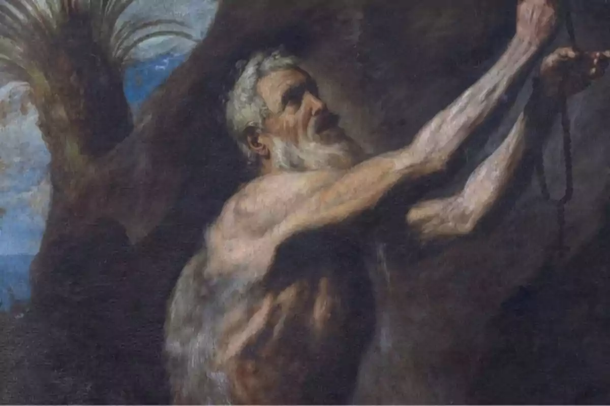 Un home ancià de barba blanca i tors nu sosté un rosari amb totes dues mans esteses cap amunt en un entorn fosc i rocós. Un home ancià de barba blanca i tors nu sosté un rosari amb totes dues mans esteses cap amunt en un entorn fosc i rocós.