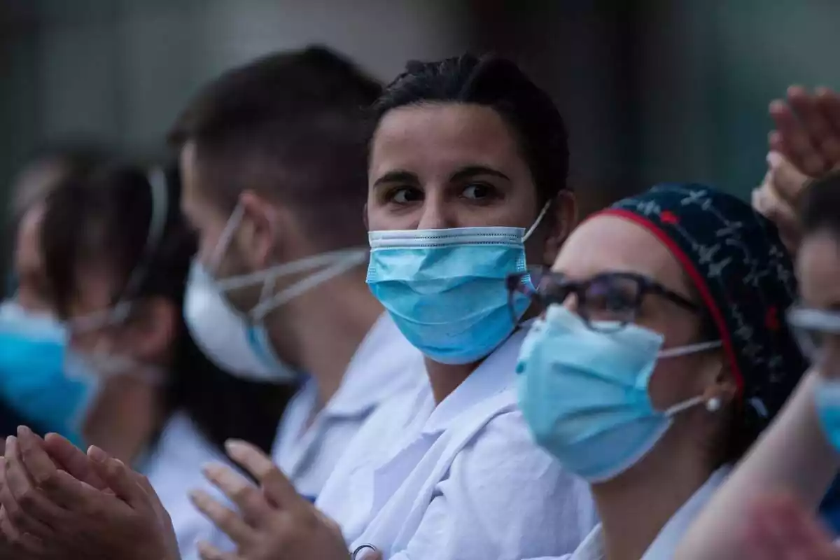 Diversos sanitaris amb màscara posada aplaudint durant la pandèmia de la Covid-19