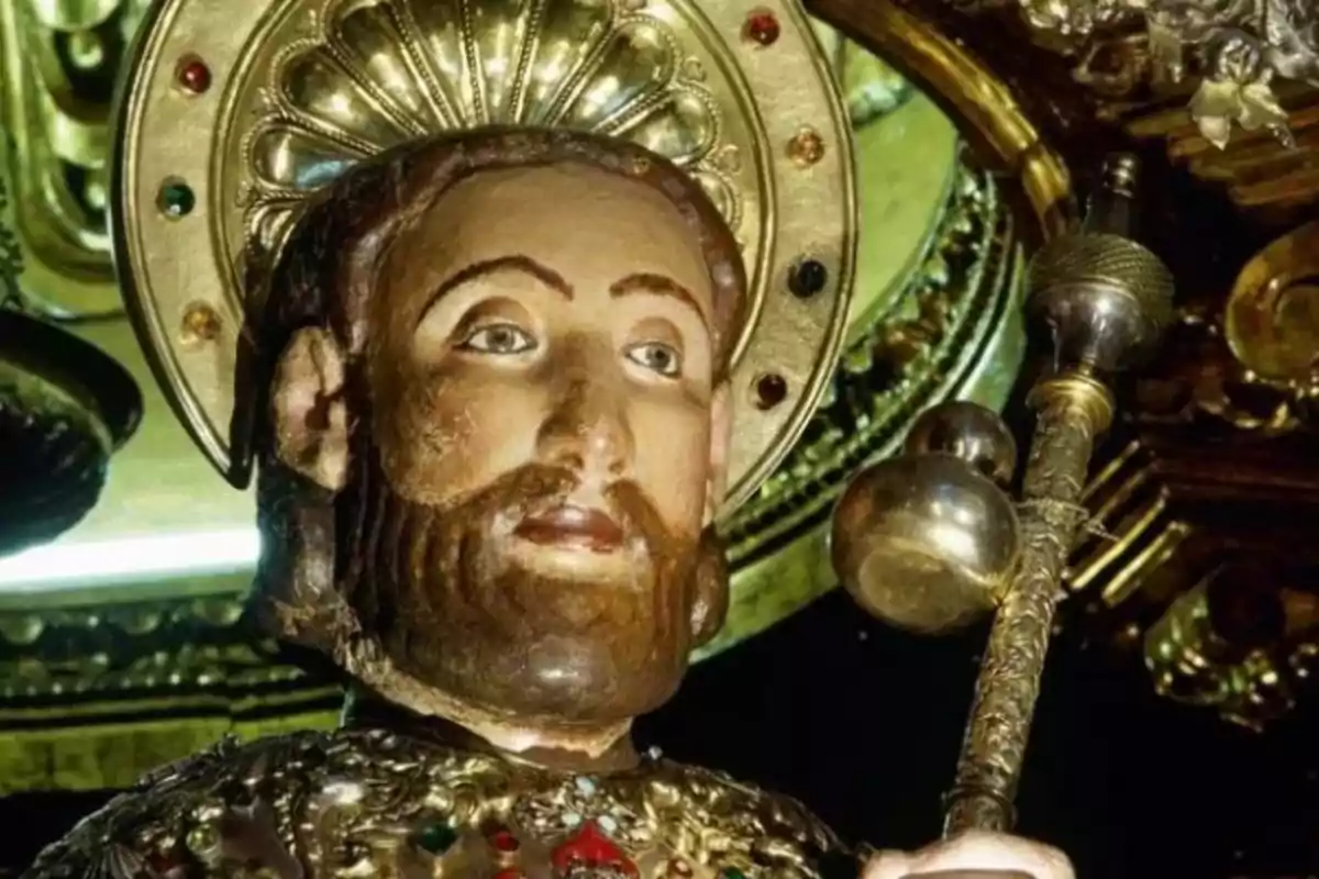 Estàtua religiosa d´un sant amb aurèola daurada i vestimenta adornada amb joies.