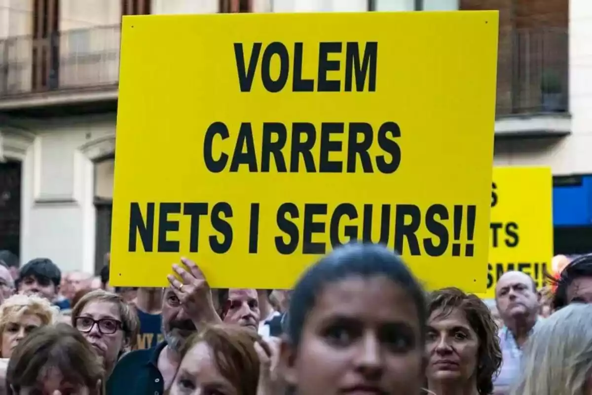 Un grup de persones en una manifestació sostenint un cartell groc amb un missatge en català.