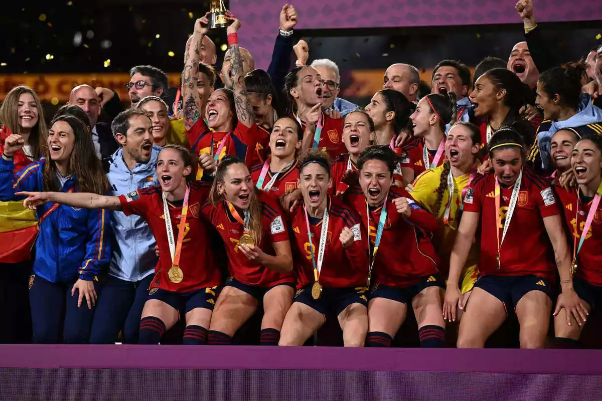 Foto de grup de la selecció espanyola de futbol femení celebrant el Mundial, amb les jugadores abraçades cridant