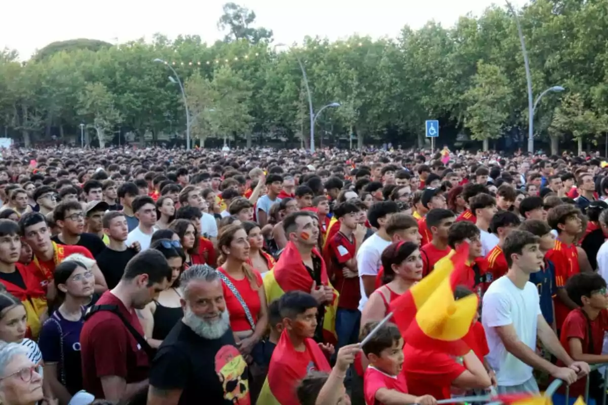 Una multitud de persones amb samarretes i banderes d?Espanya es reuneixen en un parc amb arbres al fons.