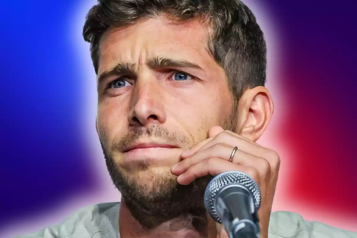 Sergi Roberto pensatiu amb un micròfon davant sobre un fons blau i vermell