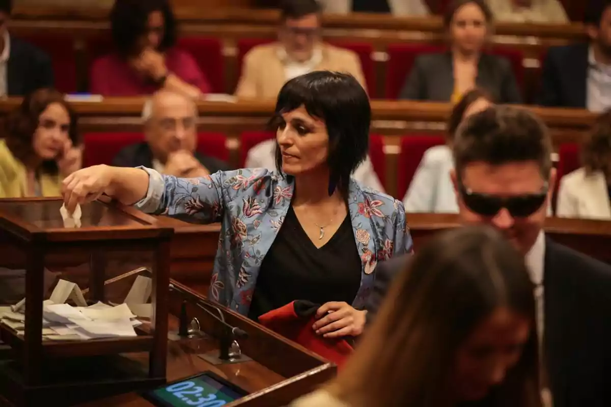 Pla mitjà de Sílvia Orriols votant al Parlament de Catalunya amb la barretina del seu avi a la mà esquerra