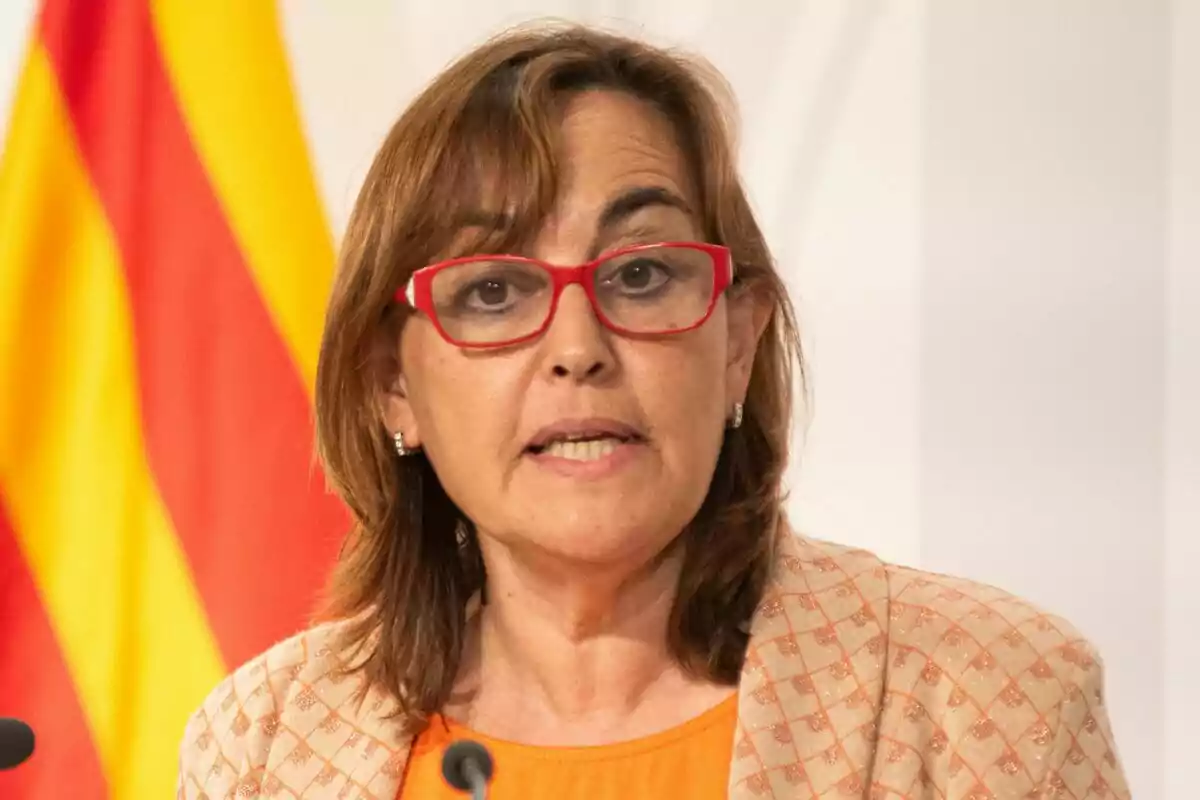 Sílvia Paneque parlant davant d'un micròfon amb una bandera de fons.