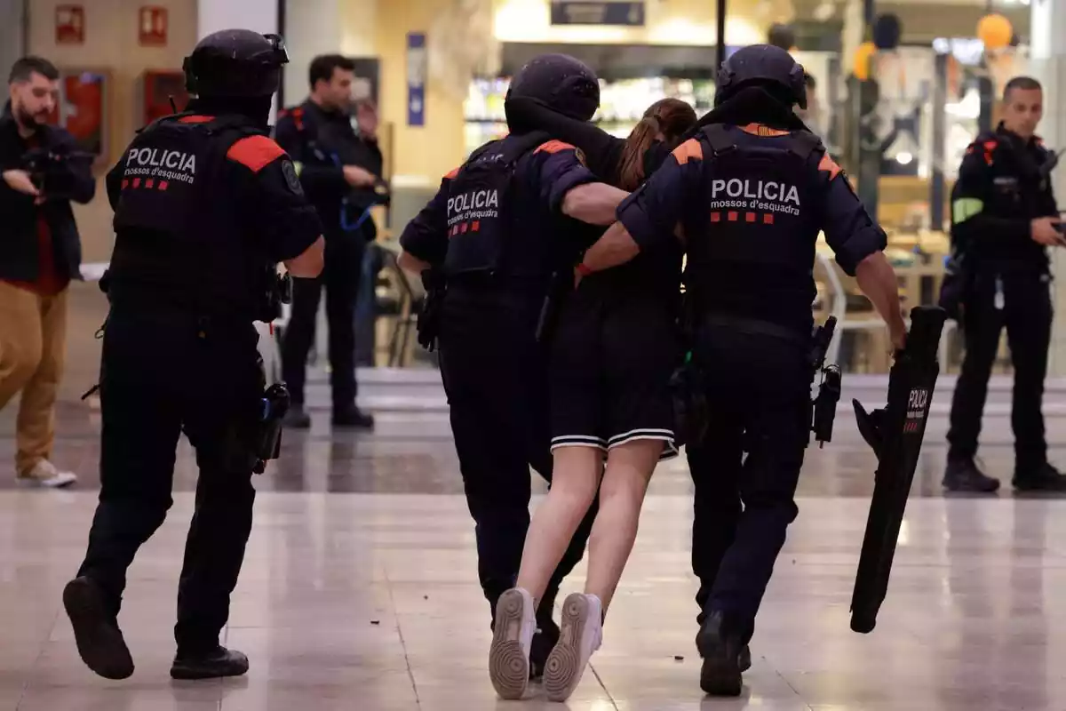 Tres Mossos d'Esquadra d'esquena, dos agafant una noia que es fa la ferida al simulacre antiterrorista fet a l'estació de Sants
