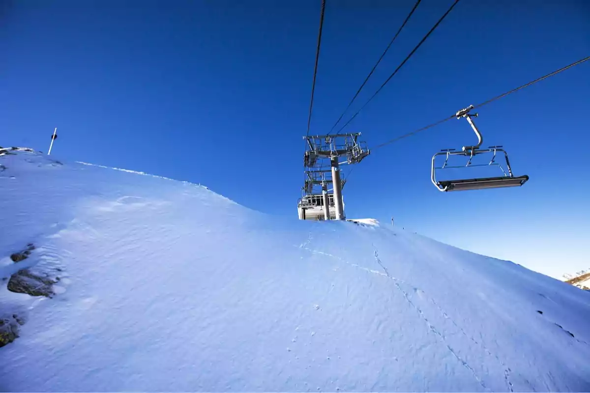 Teleférico sobre una montaña nevada bajo un cielo azul claro.