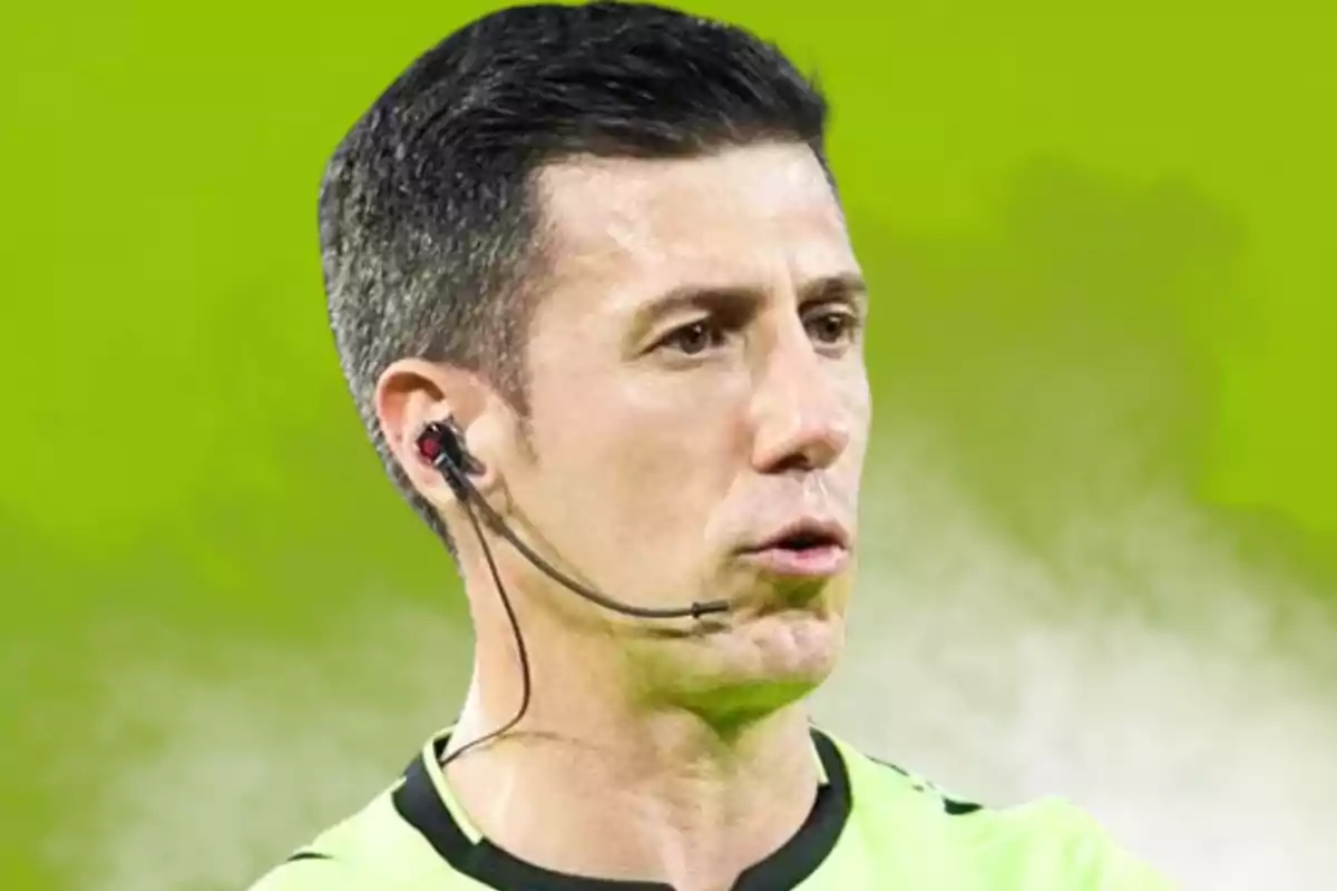 A soccer referee with an earpiece and microphone on a green background.