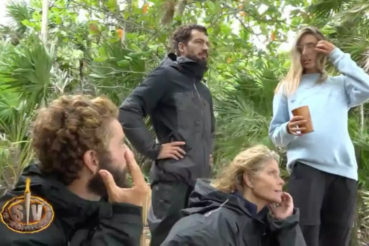 Un grup de persones vestides amb roba fosca es troba en un entorn selvàtic, envoltats de vegetació, mentre una d'elles sosté un got. Captura de 'Supervivientes'.