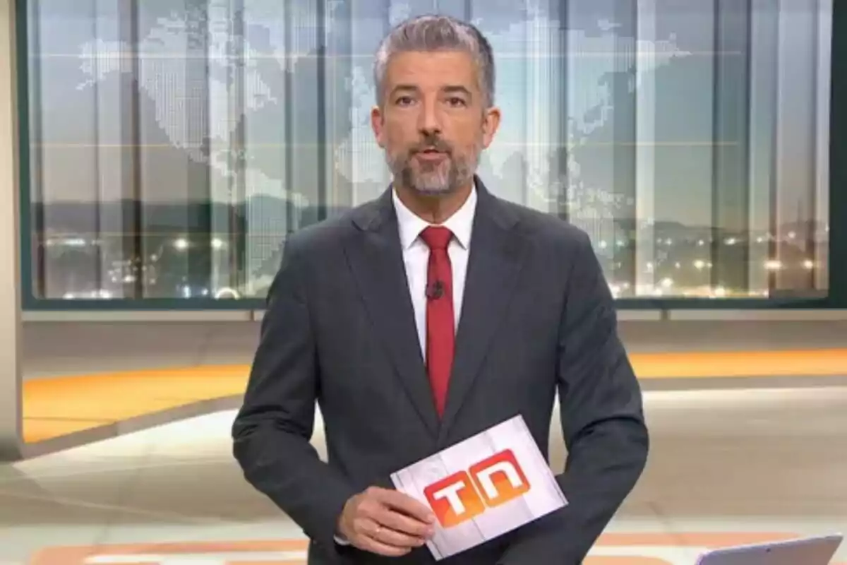 Un presentador de notícies en un estudi de televisió sostenint un paper amb el logotip de TN.