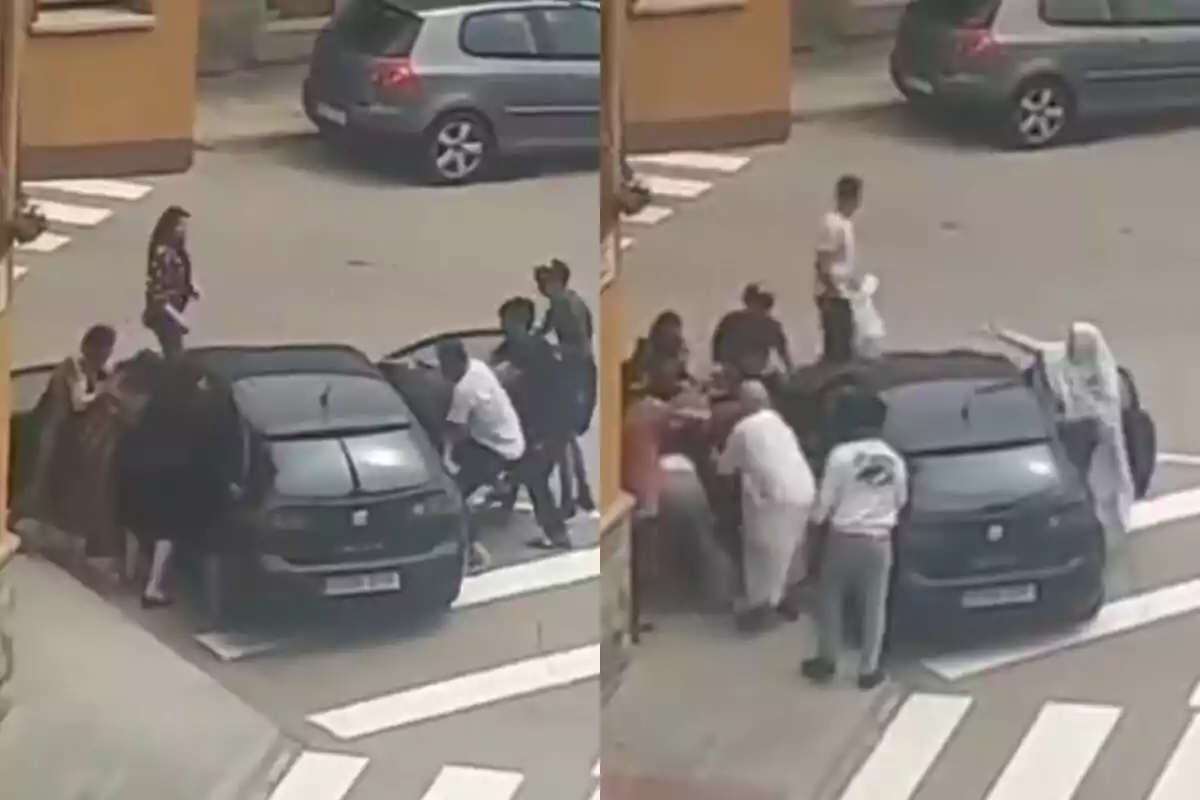 Un grup de persones estan empenyent un cotxe negre en un carrer, mentre altres observen i ajuden.