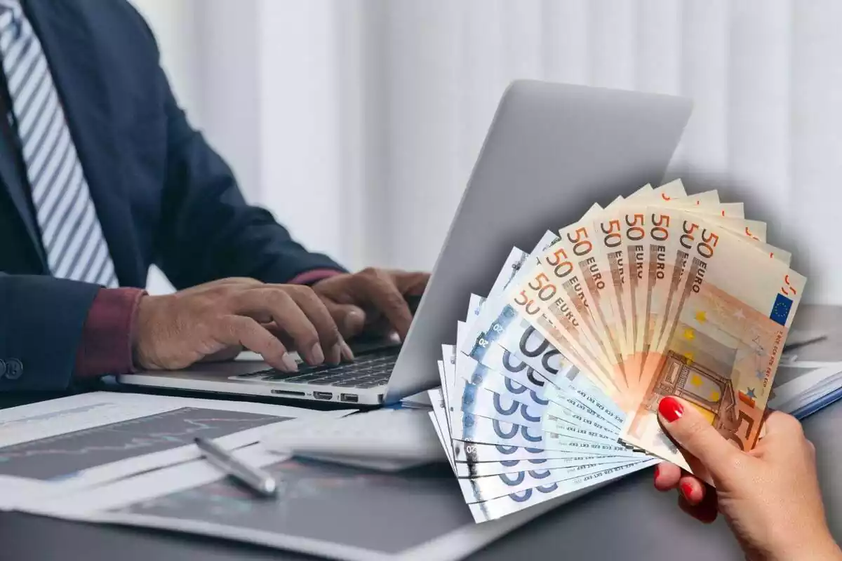 Una persona utilitzant un ordinador portàtil i una imatge superposada d'una mà sostenint diversos bitllets d'euro