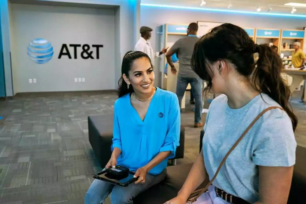Two people are talking in an AT&T store, one of them is wearing a blue uniform and holding a tablet. Two people are talking in an AT&T store, one of them is wearing a blue uniform and holding a tablet.
