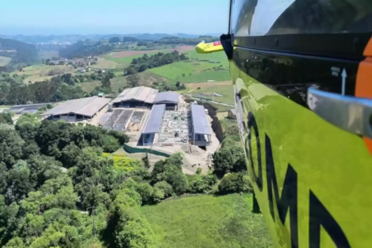 Vista aèria d’una zona rural amb edificis industrials i camps verds presa des d’un helicòpter groc