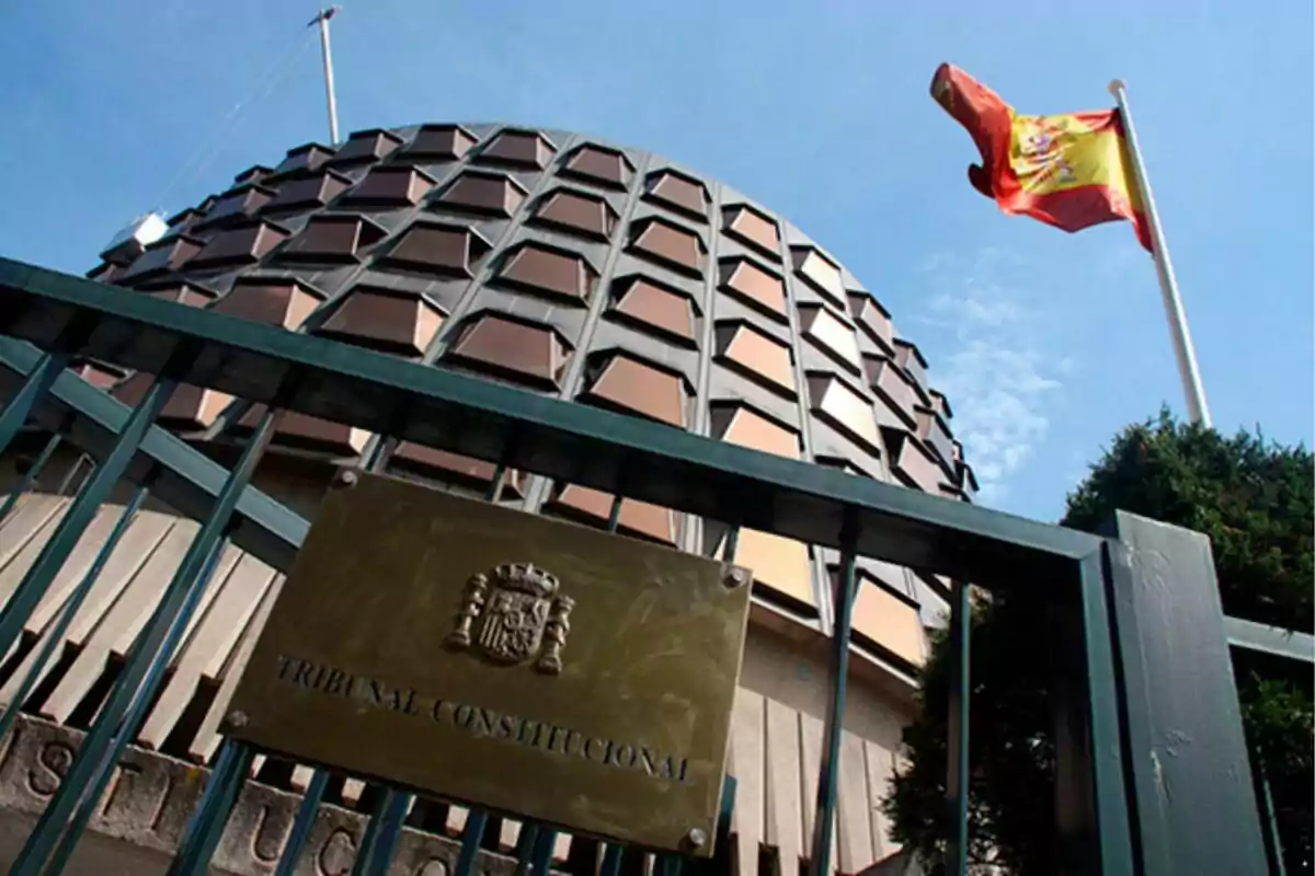Edifici del Tribunal Constitucional d'Espanya amb una bandera espanyola onejant al fons. Edifici del Tribunal Constitucional d'Espanya amb una bandera espanyola onejant al fons.