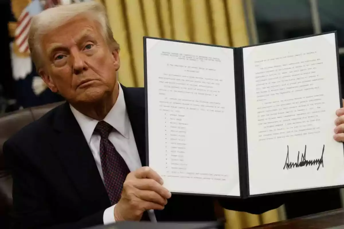 Un hombre de traje sostiene un documento abierto con texto y una firma visible.