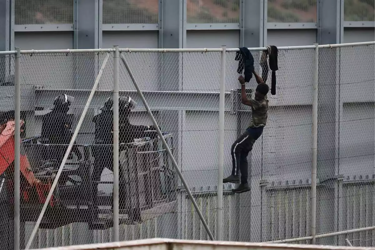 Foto d'un immigrant saltant la tanca