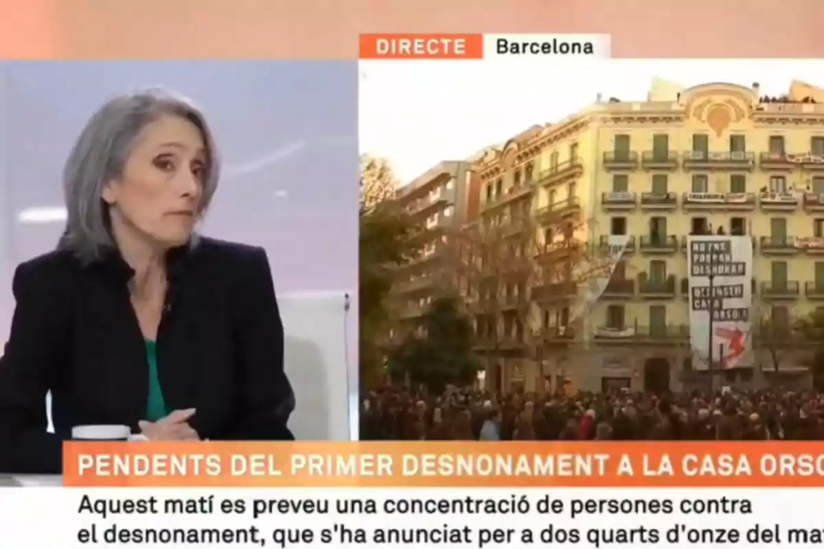 A woman in a television studio next to an image of a building in Barcelona with a crowd outside, with text on the screen about an eviction.