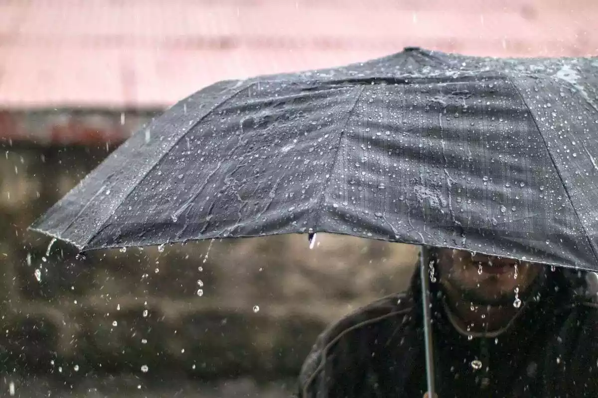 Un home sota un paraigua mentre plou