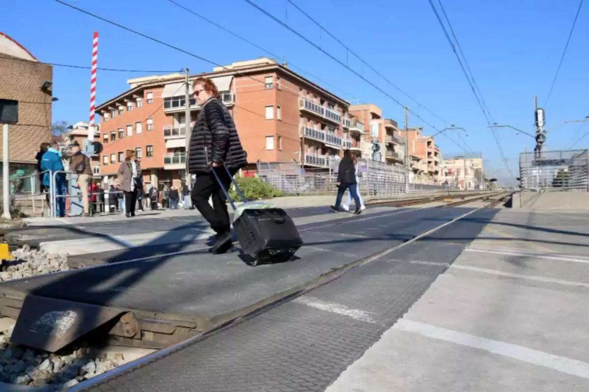 Una dona creuant el pas a nivell de les vies R2 a Montcada i Reixac (Barcelona)