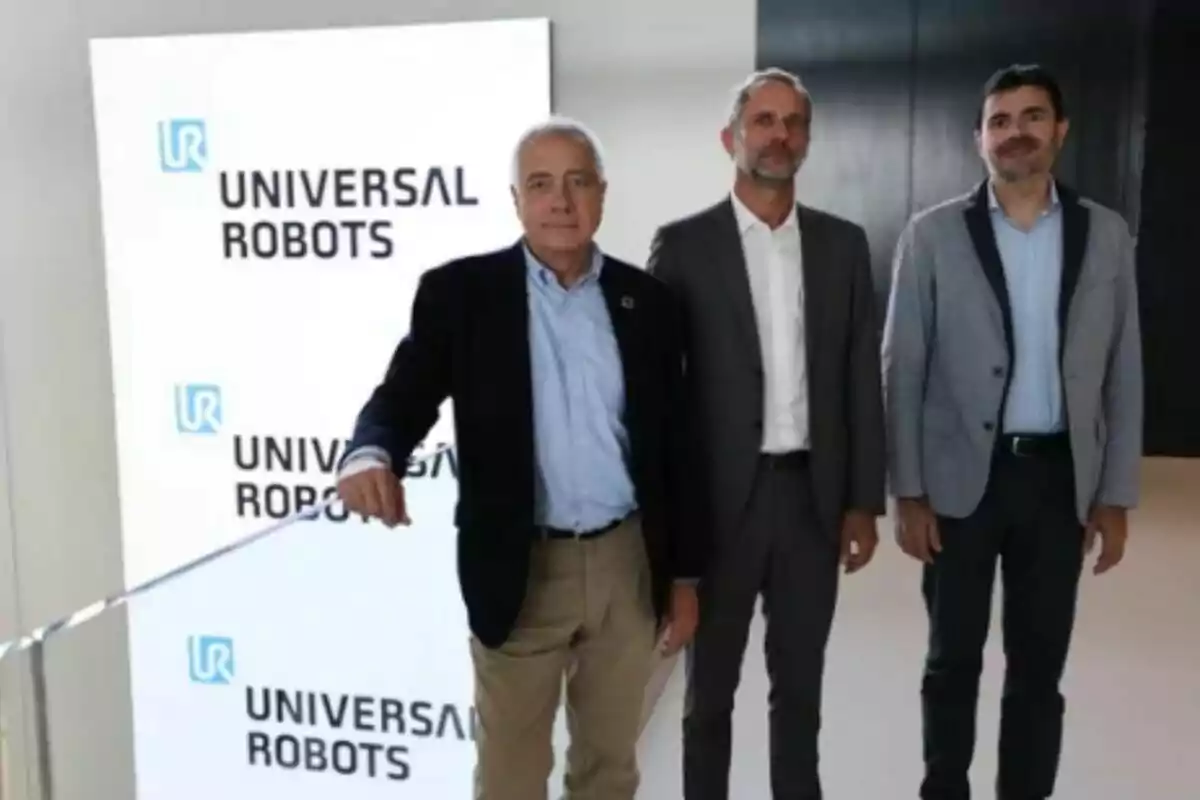 Tres homes drets davant d'un cartell d'Universal Robots.