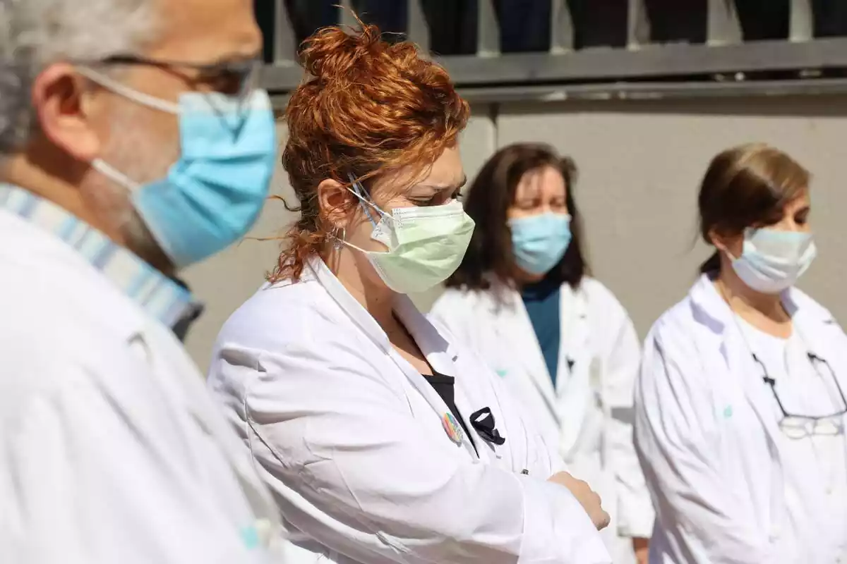 Plànol mitjà de quatre sanitaris que estan vestits amb bata blanca i porten mascareta sanitària obligatòria per combatre els contagis de coronavirus