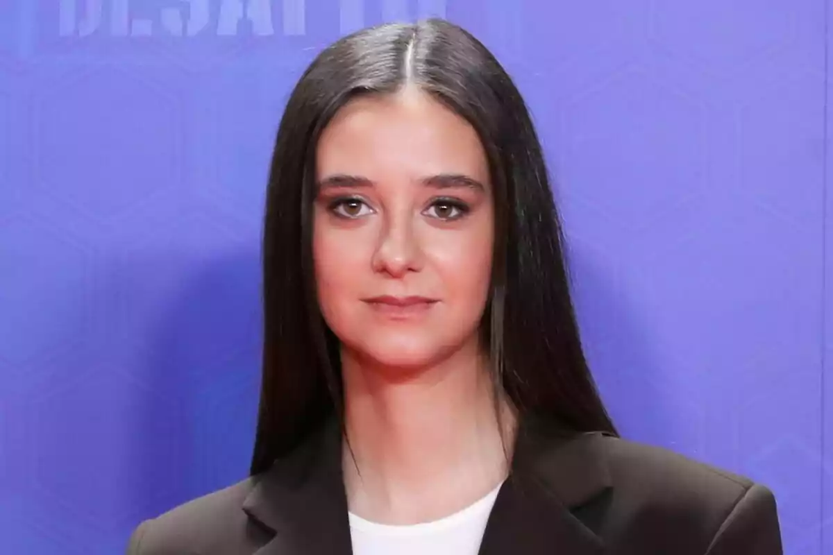 Victoria Federica con cabello largo y lacio, vistiendo un traje oscuro, posando frente a un fondo azul en la rueda de prensa de El Desafío.