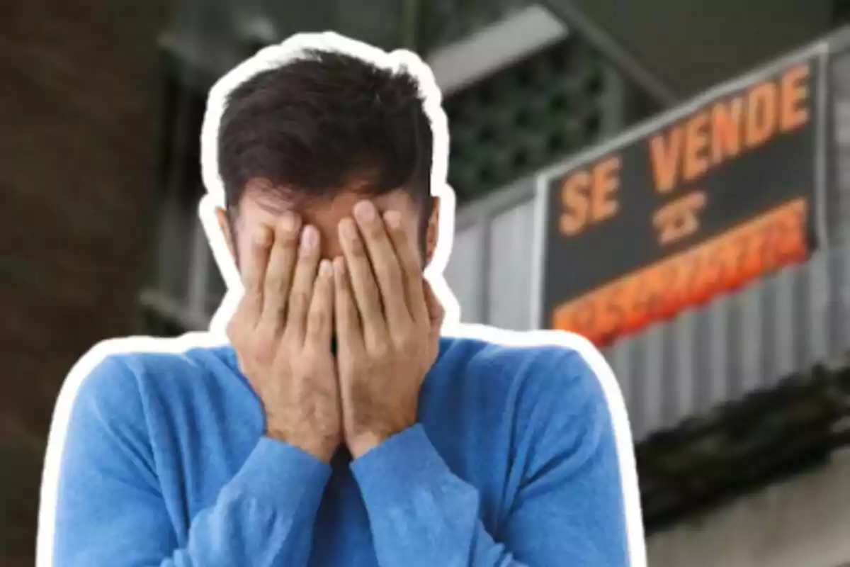 Un hombre con las manos en la cara frente a un cartel de "Se vende".