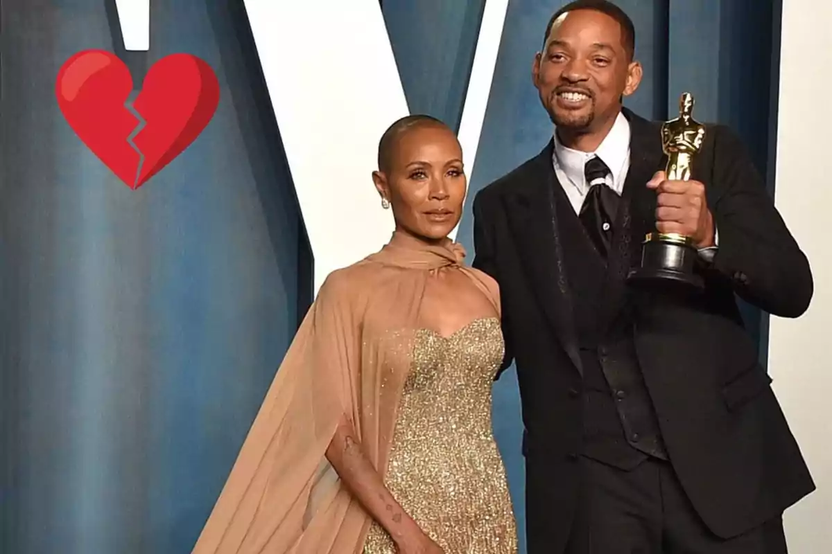 Una pareja elegantemente vestida posa en un evento, con un trofeo en la mano de uno de ellos y un emoji de corazón roto en la esquina superior izquierda.