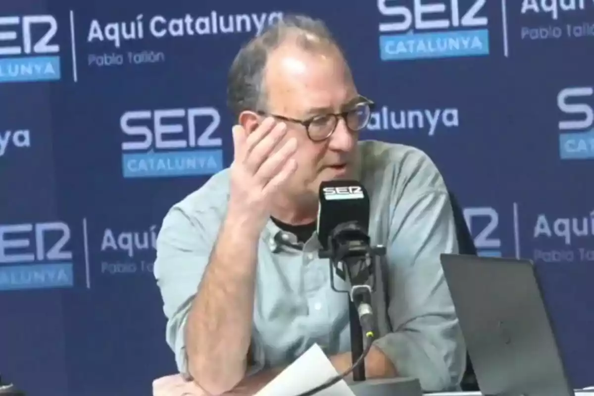 Un hombre con gafas y camisa clara habla en un micrófono de la emisora SER Catalunya en un estudio de radio.