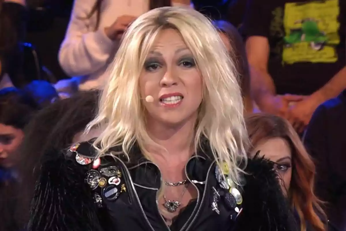 Yenesi amb perruca rossa i jaqueta amb pegats i botons està parlant en un escenari amb públic de fons a Tu Cara Me Suena.