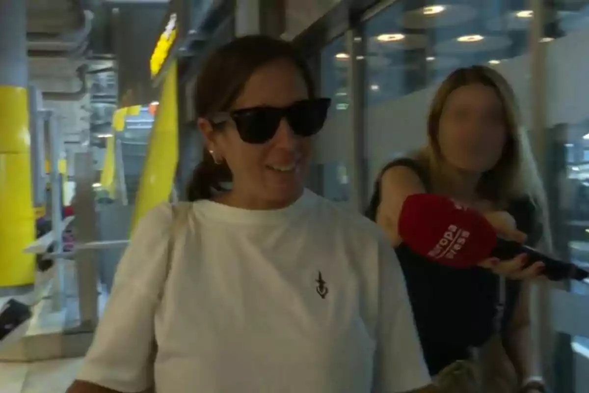 Anabel Pantoja amb ulleres de sol i samarreta blanca és entrevistada per una reportera que sosté un micròfon vermell d'Europa Press en un entorn urbà amb elements grocs i grisos. Captura de YouTube del 29 de juliol de 2024 Anabel Pantoja amb ulleres de sol i samarreta blanca és entrevistada per una reportera que sosté un micròfon vermell d'Europa Press en un entorn urbà amb elements grocs i grisos. Captura de YouTube del 29 de juliol de 2024