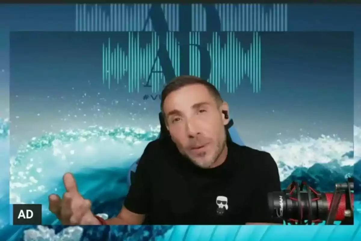 Antonio David Flores wearing headphones and a black t-shirt is speaking into a microphone with a background of waves and sound graphics. Antonio David Flores wearing headphones and a black t-shirt is speaking into a microphone with a background of waves and sound graphics.