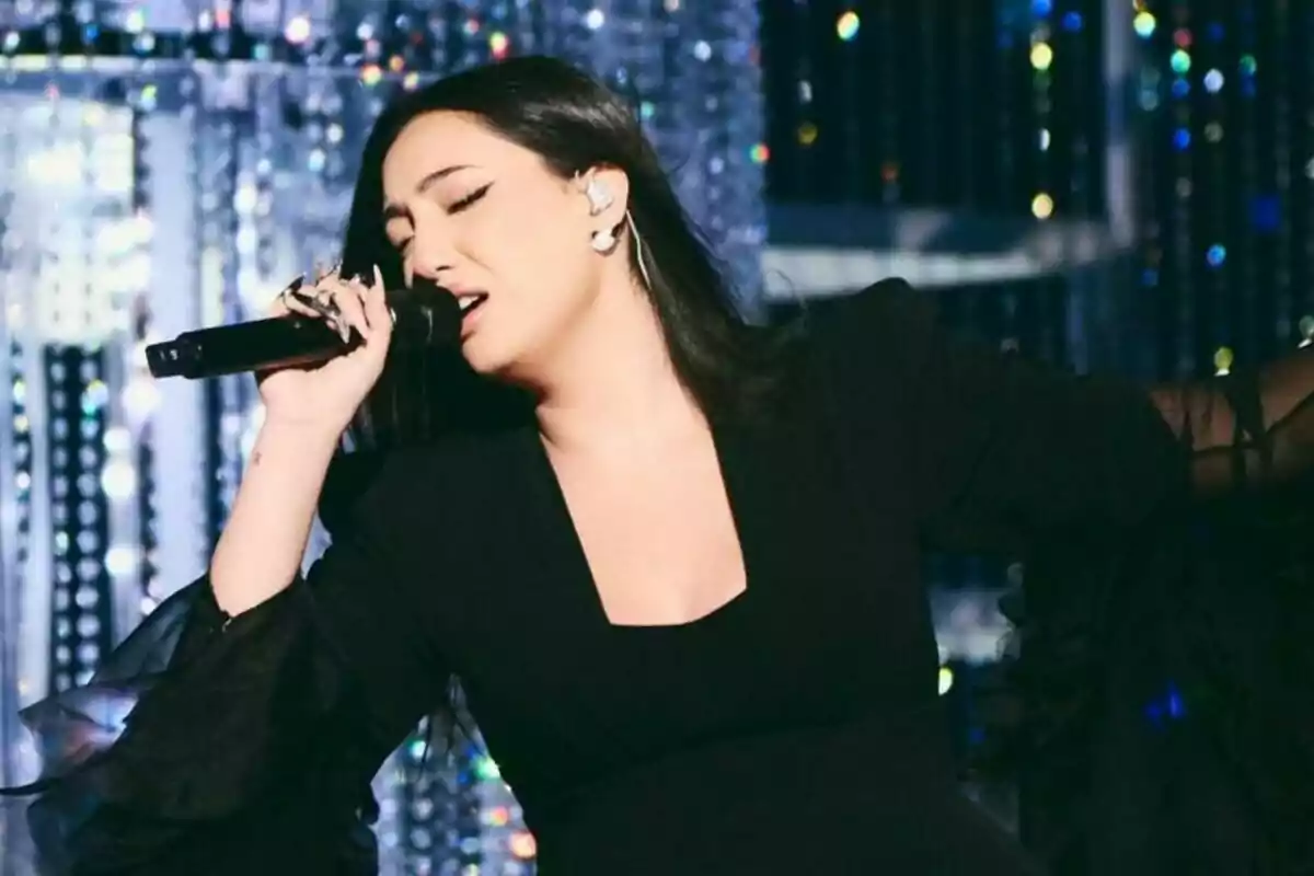Yuval, representant d'Israel a Eurovisió, cantant apassionadament a l'escenari amb un micròfon a la mà i un fons brillant.