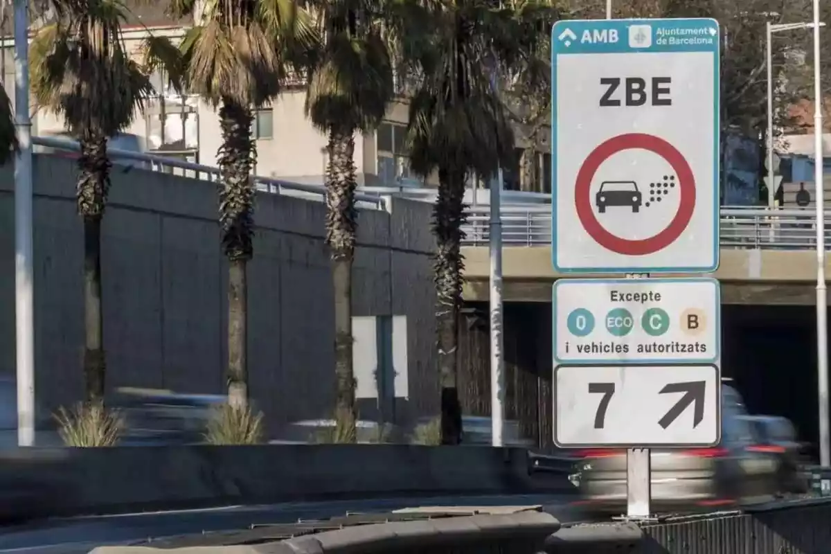 Imatge d´un cartell de Zona de Baixes Emissions i de fons una carretera amb diversos cotxes passant a alta velocitat