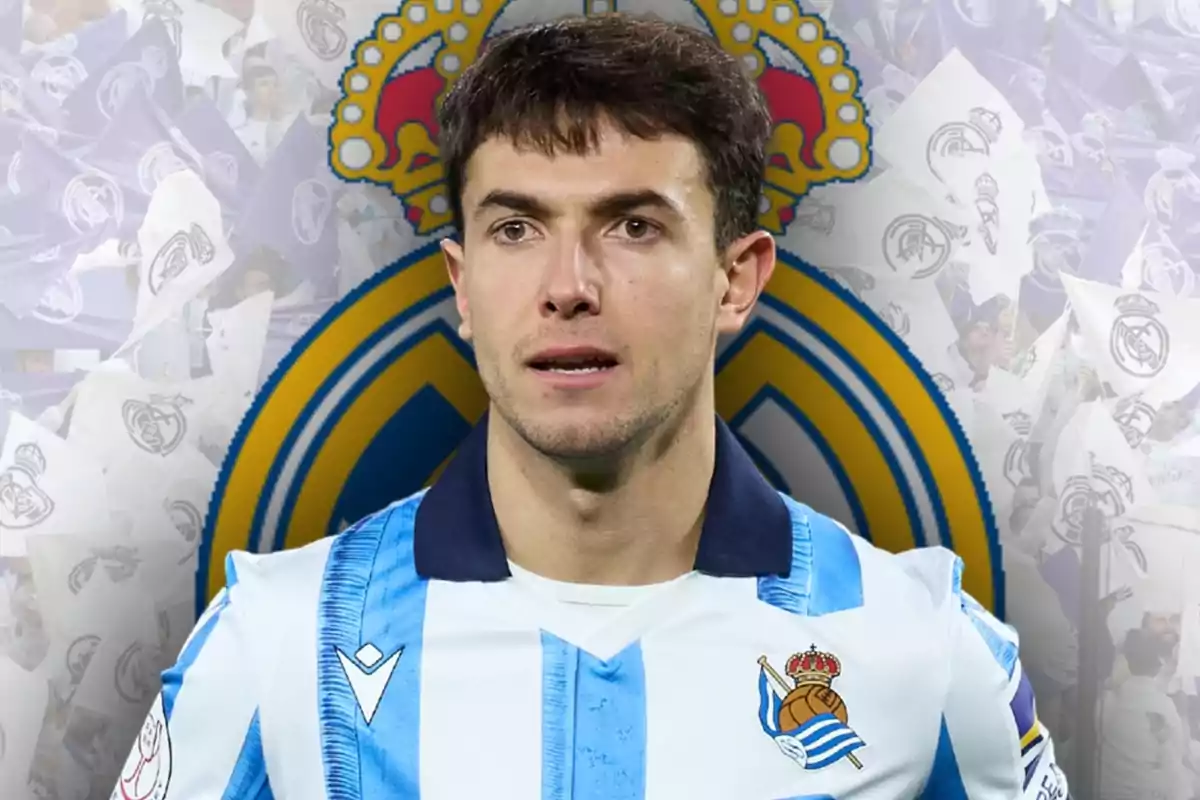 Futbolista con uniforme de la Real Sociedad frente a un fondo con el escudo del Real Madrid y aficionados ondeando banderas blancas